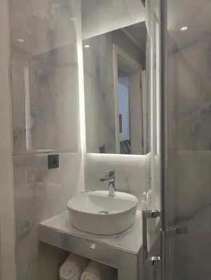 a white bathroom with a sink and a mirror at Rhodes City Haven in Rhodes Town