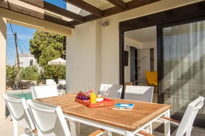 a wooden table and chairs on a patio with a table at Villa Laila in Ialyssos
