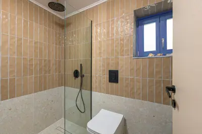 a bathroom with a shower with a toilet and a window at Villa fiore in Rhodes Town
