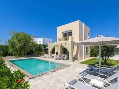 a villa with a swimming pool and chairs and an umbrella at Holiday Home Liebevoll ausgestattetes Haus in ruhiger Lage mit beheiztem Pool und Meerblick by Interhome in Gennadi