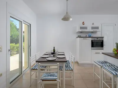 a dining room with a table and chairs and a kitchen at Holiday Home Liebevoll ausgestattetes Haus in ruhiger Lage mit beheiztem Pool und Meerblick by Interhome in Gennadi