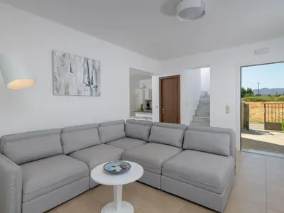 a living room with a couch and a table at Holiday Home Liebevoll ausgestattetes Haus in ruhiger Lage mit beheiztem Pool und Meerblick by Interhome in Gennadi