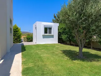 a white house with a tree in the yard at Holiday Home Liebevoll ausgestattetes Haus in ruhiger Lage mit beheiztem Pool und Meerblick by Interhome in Gennadi