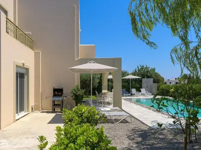 a patio with an umbrella and a swimming pool at Holiday Home Liebevoll ausgestattetes Haus in ruhiger Lage mit beheiztem Pool und Meerblick by Interhome in Gennadi