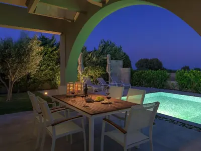 a dining area with a table and chairs and a pool at Holiday Home Liebevoll ausgestattetes Haus in ruhiger Lage mit beheiztem Pool und Meerblick by Interhome in Gennadi