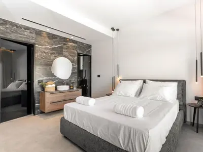 a bedroom with a large white bed and a bathroom at Holiday Home Emerald Estate by Interhome in Asgourou