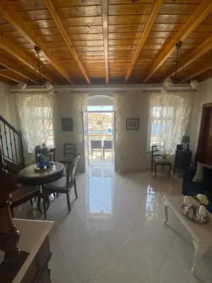 a living room with wooden ceilings and tables and chairs at Hermes Traditional house in Gialos in Symi