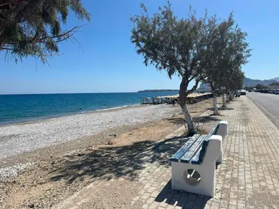 a bench sitting on the side of a beach at Eirēnē house Afantou in Afantou