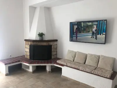 a living room with a couch and a tv on the wall at Eirēnē house Afantou in Afantou