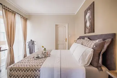 a bedroom with a large white bed with a table at Russelia Suite right in the heart of Rhodes City in Rhodes Town