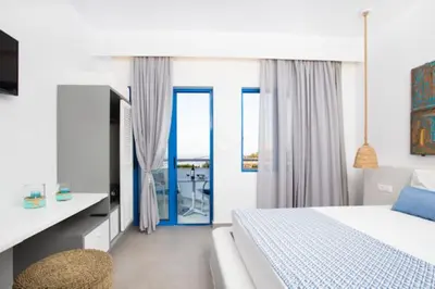 a bedroom with a bed and a desk and a window at Lindos Portes Blue in Líndos