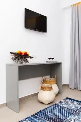 a white table with a television on a wall at Lindos Portes Blue in Líndos