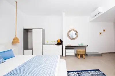 a white bedroom with a bed and a desk at Lindos Portes Blue in Líndos