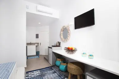 a white kitchen with a counter and a tv on the wall at Lindos Portes Blue in Líndos