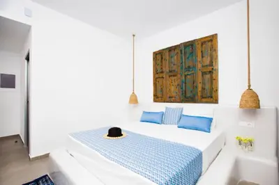 a white room with a bed with blue pillows at Lindos Portes Blue in Líndos