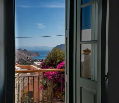 a door to a balcony with a view of the ocean at Symi Village House in Symi