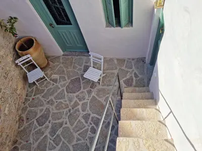two chairs and a door and stairs in front of a house at Symi Village House in Symi
