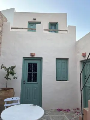 a white building with a green door and a table at Symi Village House in Symi