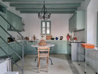 a kitchen with green cabinets and a table and a chandelier at Symi Village House in Symi