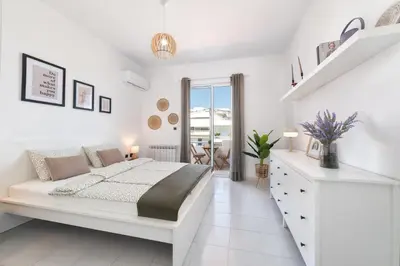 a white bedroom with a bed and a staircase at Ferienwohnung BIA Rigas in Rhodes Town