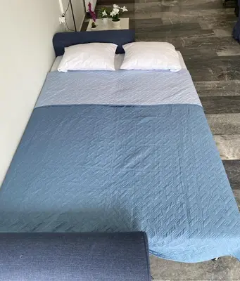 a bed with a blue blanket on top of it at Diogenis seaside apartment in Rhodes Town