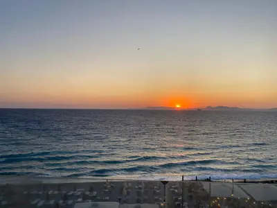 a sunset over the ocean with a cruise ship at Diogenis seaside apartment in Rhodes Town