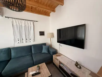 a living room with a blue couch and a flat screen tv at Spitaki in Kremasti