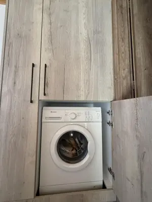 a washing machine in a kitchen with wooden cabinets at Spitaki in Kremasti