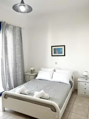 a white bedroom with a bed with white pillows at Blue View in Livadia