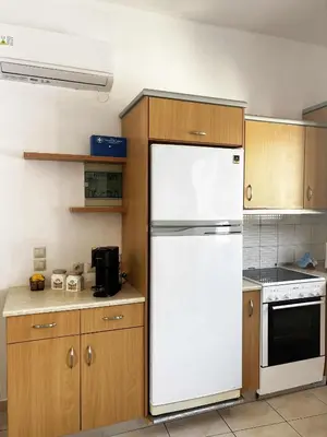 a kitchen with a white refrigerator and wooden cabinets at Blue View in Livadia