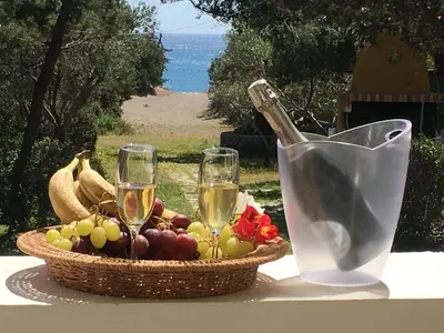 a basket of fruit and two glasses of wine on a table at Beachfront Villa Rhodes SeaShell in Gennadi
