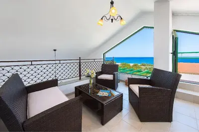 a balcony with chairs and a table and a view of the ocean at Beachfront Villa Rhodes SeaShell in Gennadi