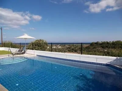 a swimming pool with a chair and an umbrella at Villa Fig Tree in Phanaes