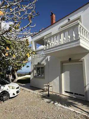 a white house with a car parked in the driveway at Villa Fig Tree in Phanaes