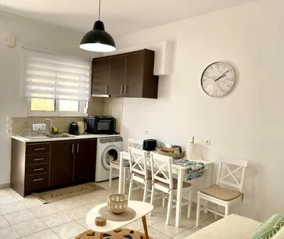 a kitchen with a table and a clock on the wall at Andreana s View House Rhodes in Asgourou