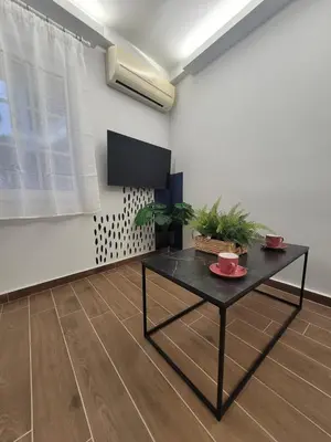 a living room with a table and a tv at Hyacinthus city apartment in Rhodes Town