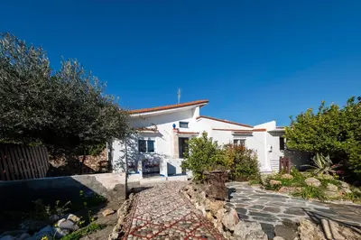 a white house with a pathway in front of it at Aelia Filoxenia Cottage in Afantou