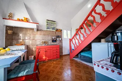 a kitchen with red cabinets and a red staircase at Aelia Filoxenia Cottage in Afantou