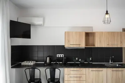a kitchen with black tiled walls and wooden cabinets at K Studios in Faliraki