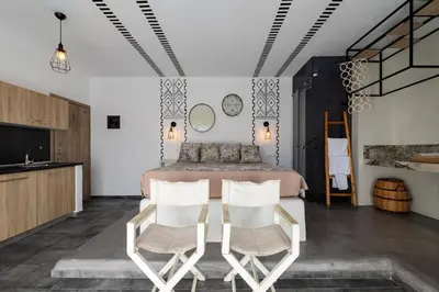 a bedroom with a bed and two white chairs at K Studios in Faliraki