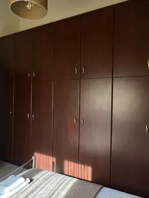 a bedroom with brown cabinets and a bed at TheraLiving - Boutique Apartment with Balcony in Afantou