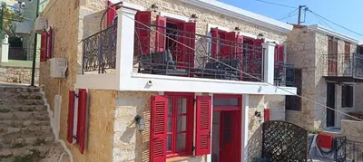 a building with red shutters and a balcony at Elena Studio in Halki