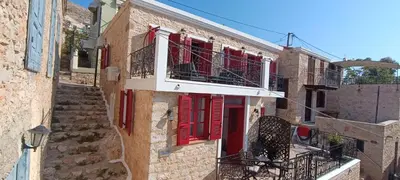 an old building with red shutters and a staircase at Elena Studio in Halki