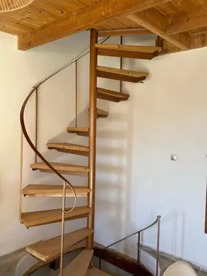 a spiral staircase in a room with a wooden ceiling at Maria's Dream House in Symi