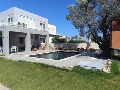 a villa with a swimming pool in front of a house at Casa Fountain Villa in Kolimbia