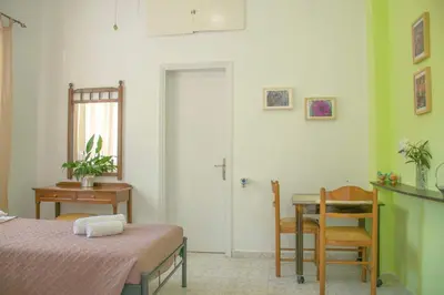 a room with two beds and a table and a door at Palm Residence l - Islander's Home Collection in Rhodes Town
