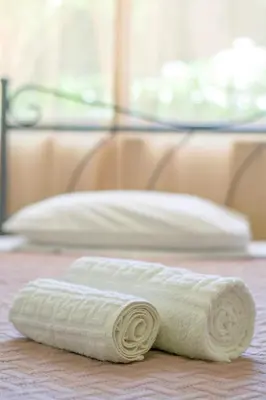 a rolled up white towel sitting on a bed at Palm Residence l - Islander's Home Collection in Rhodes Town