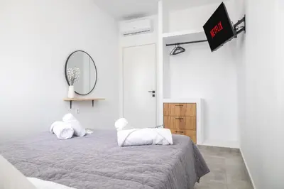 a white bedroom with a bed and a mirror at maison de rivière in Afantou