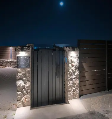 a gate at night with the moon in the background at Aelios Petra sea view apartment 3 in Asgourou
