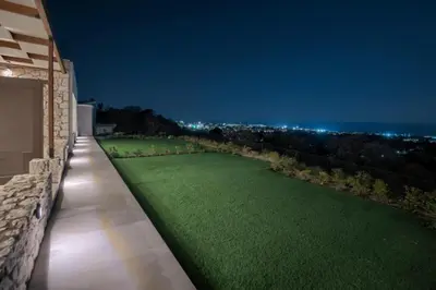 a lawn on the side of a house at night at Aelios Petra sea view apartment 3 in Asgourou